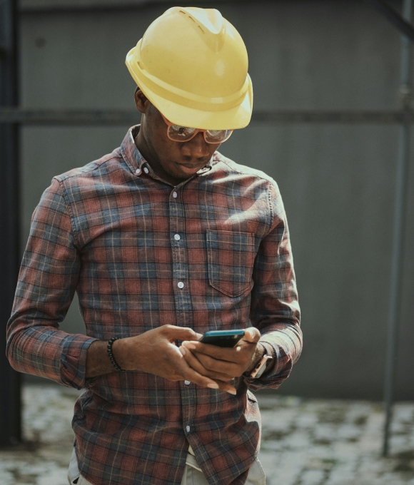 Portrait of a black man architect at a building site looking at camera. Confident civil engineering wearing a hardhat and eye goggles. Successful mature civil engineer at a construction site