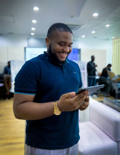 A man is happy looking at his iPad and holding it as well.